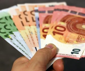 A fan of euro banknotes in various denominations held in a hand.